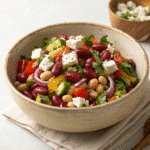 No-lettuce bean salad in a bowl with beans, tomatoes, cucumber, olives, onion, and feta