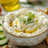 Whipped cottage cheese dip with vegetables and pita chips on a rustic board