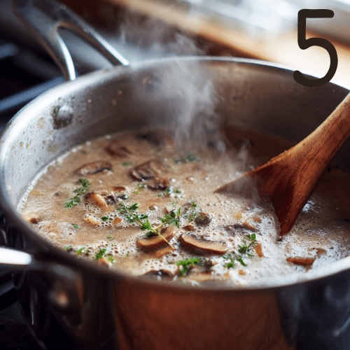 Gluten-free creamy mushroom soup simmering in a stainless steel pot with steam rising.