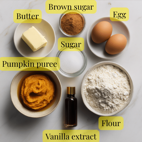 Pumpkin cookie ingredients arranged on marble – butter, brown sugar, granulated sugar, pumpkin puree, egg yolk, vanilla, and flour in bowls