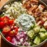 Delicious Greek Chicken Bowls topped with fresh vegetables and feta cheese