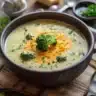 Bowl of creamy Broccoli Cheese Soup topped with cheese and fresh broccoli.
