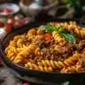 A bowl of creamy cheeseburger pasta topped with cheese and fresh herbs
