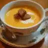 Delicious creamy pumpkin soup served in a bowl with herbs on top