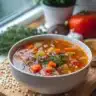 A bowl of Grandma's hearty vegetable soup filled with fresh vegetables.