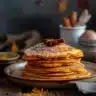 Delicious homemade pumpkin pancakes topped with maple syrup and whipped cream