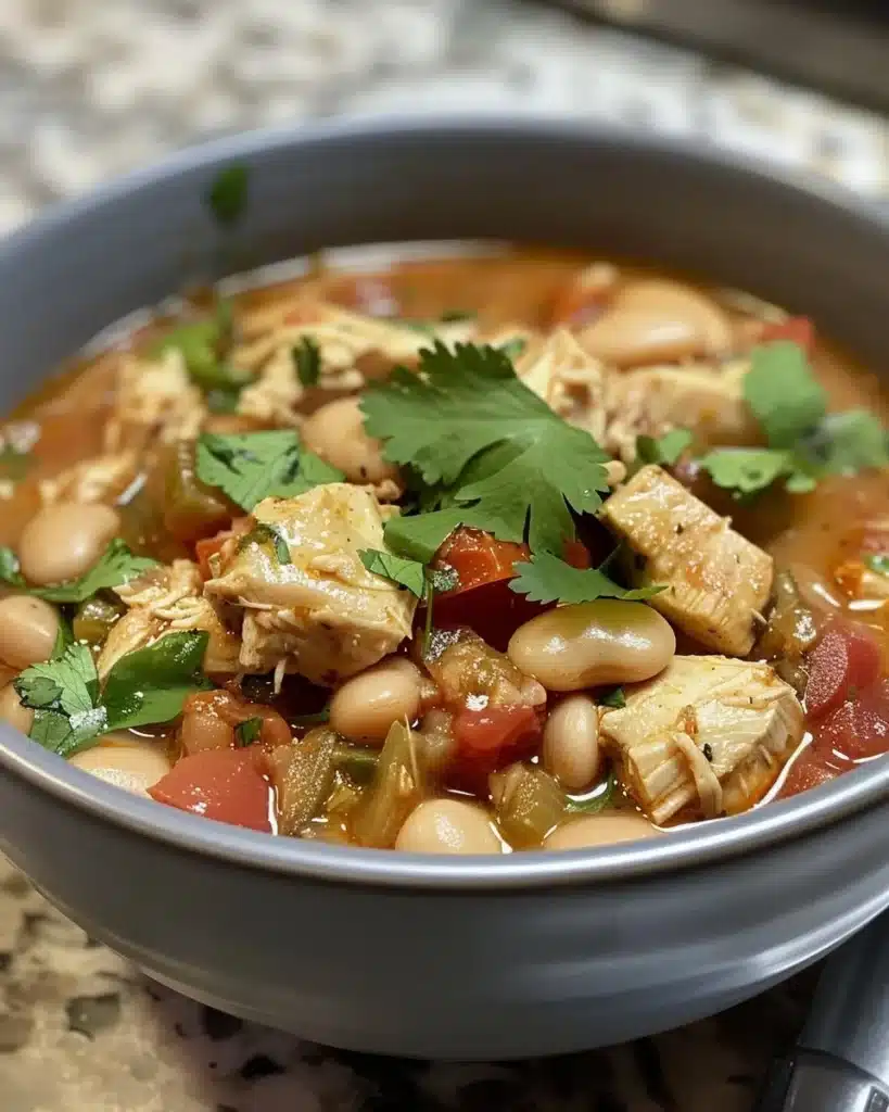 Bowl of Cha Cha's Chili with White Beans and Chicken garnished with herbs