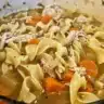 Bowls of homemade chicken noodle soup with vegetables and herbs