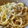 A plate of creamy garlic parmesan pasta topped with fresh parsley and grated cheese.