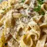 Delicious plate of French Onion Pasta garnished with herbs and cheese.