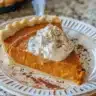 Delicious slice of homemade pumpkin pie with whipped cream on top