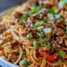 Asian-style ground beef spaghetti garnished with green onions