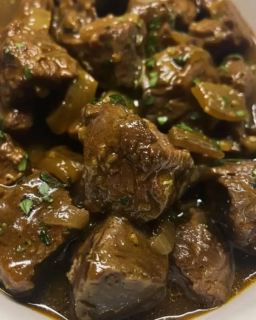 Savory beef tips served in rich gravy on a plate with fresh herbs.