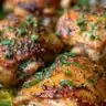 Delicious bone-in baked chicken thighs served on a plate with herbs and spices.