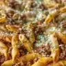 Delicious Cheesy Beef Penne served in a bowl with melted cheese topping.