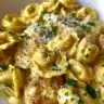 Creamy herb chicken tortellini dish garnished with fresh herbs