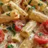 A bowl of creamy rigatoni pasta with sauce and herbs