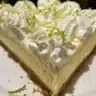 Slice of Key Lime Pie with Cream Cheese garnished with lime and whipped cream