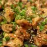 Plate of Mongolian Chicken garnished with green onions and sesame seeds