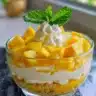 Delicious no bake mango cheesecake cups topped with fresh mango slices.