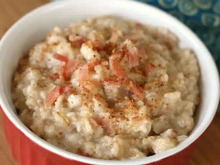 Bowl of savory breakfast oatmeal topped with vegetables and herbs