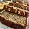 Slice of moist Banana Nut Cake topped with walnuts and drizzled with glaze