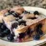 Blueberry cupcakes drizzled with vanilla sauce on a rustic plate