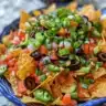 Delicious campfire nachos served in a skillet with melted cheese and toppings