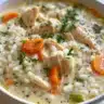 Delicious bowl of creamy chicken and rice soup garnished with herbs.