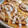 A delectable giant cinnamon roll cake topped with creamy icing and cinnamon swirl.