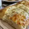 Homemade pull-apart bread with herbed cream cheese served on a wooden board.