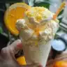 Refreshing Orange Julius drink in a clear cup with orange slices.