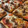 Slice of rectangle school pizza on a plate, showcasing its cheesy goodness and toppings.