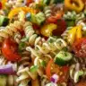 Colorful rotini pasta salad with fresh vegetables and dressing in a bowl