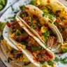 Smashed breakfast tacos filled with eggs, cheese, and salsa, served on a plate.