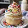 Delicious sprinkle cupcakes topped with colorful sprinkles on a white plate.