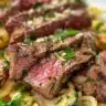 Surf & Turf Garlic Noodles with seafood and meat garnished with herbs