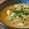 Bowl of creamy Apple and Cheese Soup garnished with fresh herbs
