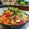 Bowl of Asian noodle salad with vibrant vegetables and peanut dressing
