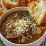 Delicious bowl of French Onion Soup topped with melted cheese and herbs