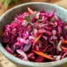 Bowl of vibrant red borscht topped with sour cream and fresh herbs.
