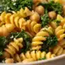 A vibrant bowl of Caesar Kale Pasta Salad featuring fresh ingredients and dressing