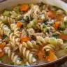 Bowl of homemade chicken soup with vegetables and herbs