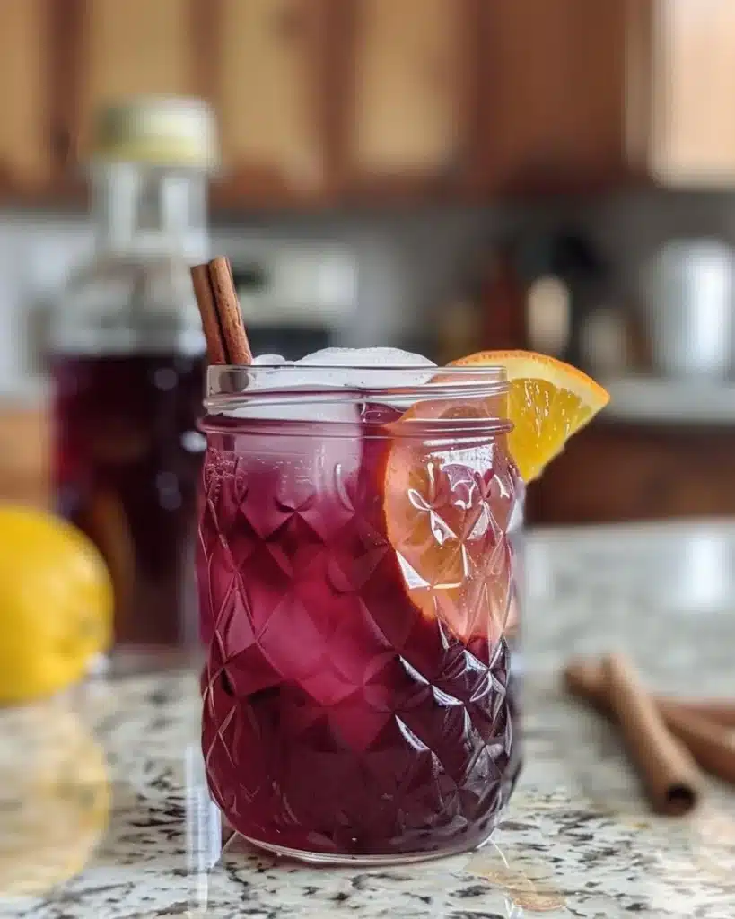 Chilled Hibiscus Coconut Milk Tea in a glass with ice and tropical fruits
