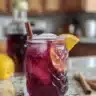 Chilled Hibiscus Coconut Milk Tea in a glass with ice and tropical fruits