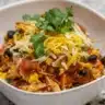 Bowl of creamy Chicken Enchilada Soup garnished with cilantro and tortilla strips.
