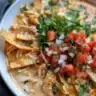 Bowl of creamy chicken tortilla soup topped with tortilla strips and cilantro.