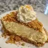 Creamy pumpkin cheesecake slice topped with whipped cream and pumpkin spice.