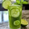 Cucumber lime infused water in a clear pitcher with fresh ingredients