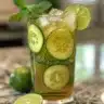 Beverage of cucumber lime water served in a glass with fresh cucumber slices